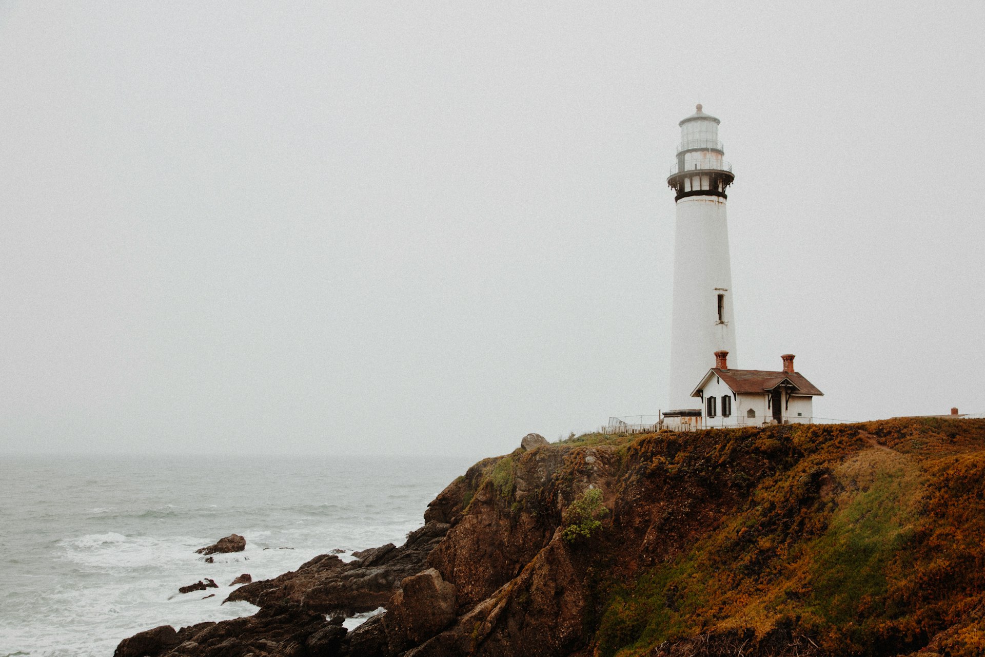 white lighthouse on rocky cliff